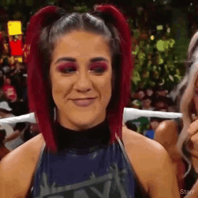 a woman with red hair is smiling in front of a crowd while standing in a ring .