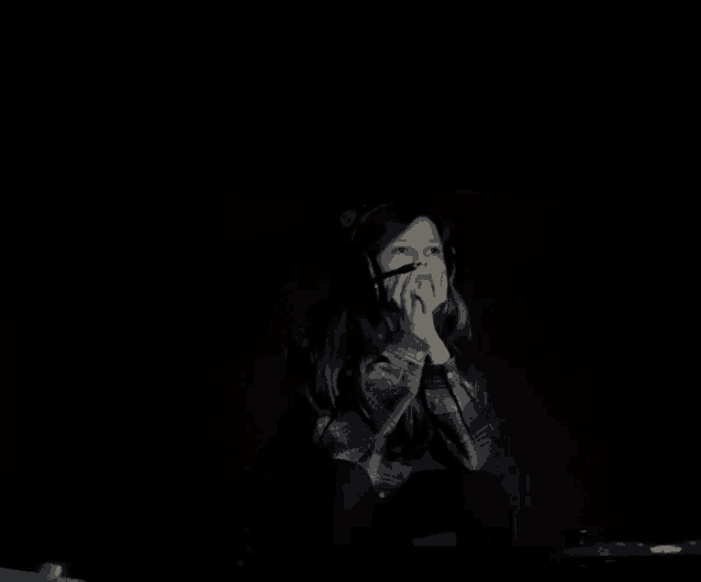 a young girl wearing headphones looks up at something in the dark
