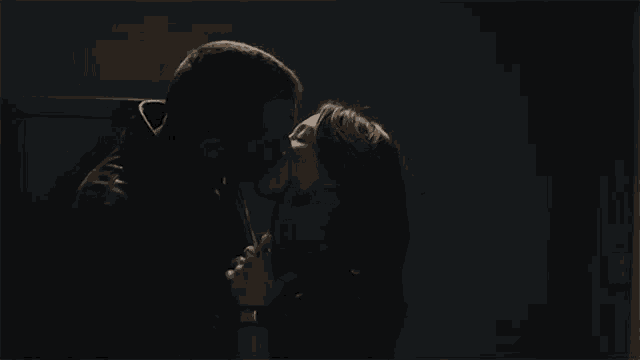 a man and a woman are kissing in the dark