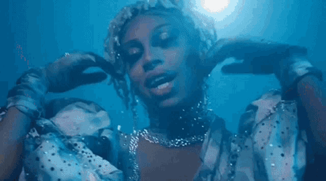 a close up of a drag queen wearing a blue jacket and a silver wig .