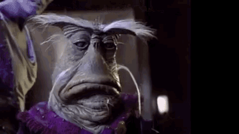 a close up of a strange creature with a mustache and a purple shirt .