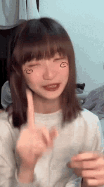 a girl with a drawing of a heart on her face is giving the middle finger
