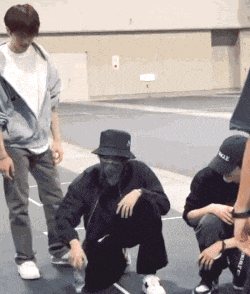 a man wearing a hat that says vogue sits on the ground