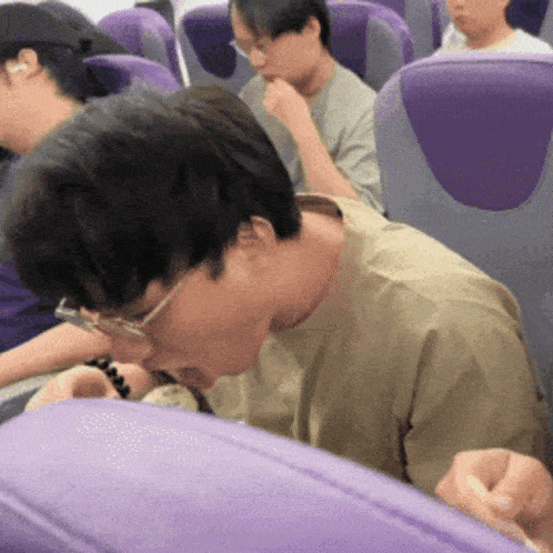 a man with glasses is sitting in a purple seat