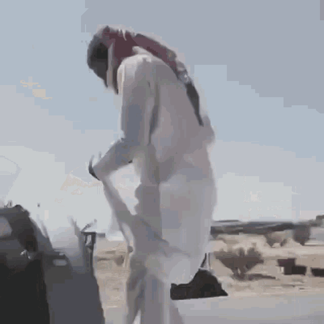 a man in a white hat is standing next to a white truck in the desert .