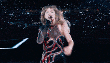 a woman is singing into a microphone in front of a crowd