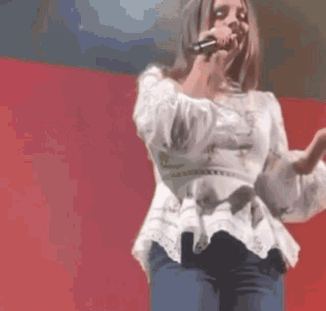 a woman is singing into a microphone on stage .