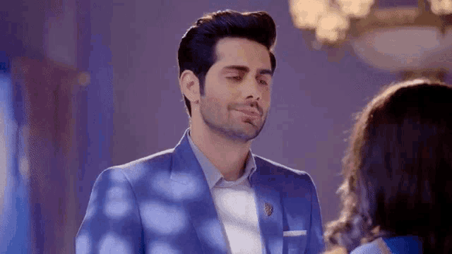 a man in a blue suit is looking at a woman in a room .