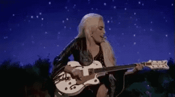 a woman is playing a guitar under a starry sky .