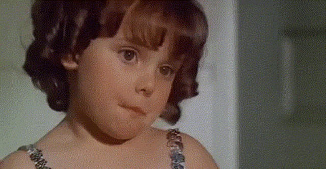 a little girl with a necklace on her neck looks at the camera
