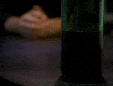 a man is looking at a green bottle of alcohol