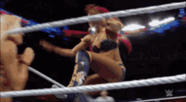 a woman in a bikini is wrestling another woman in a wrestling ring ..