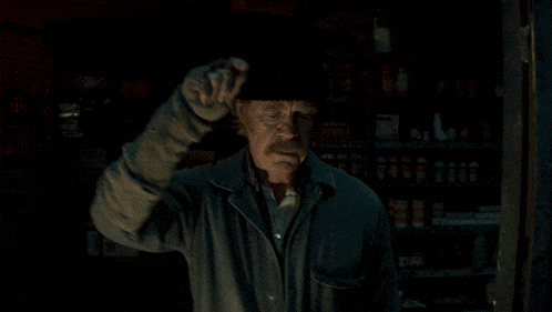 an older man wearing a beanie stands in front of a shelf full of boxes and bottles