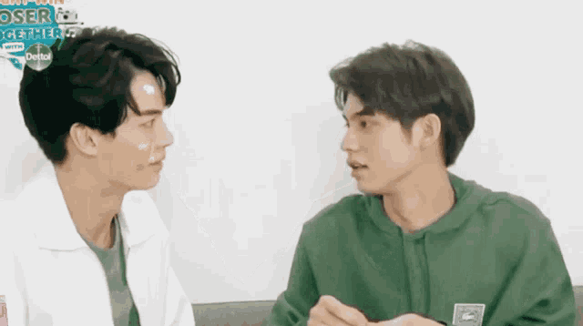 two men are looking at each other with a dettol logo in the background .