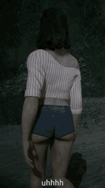 a woman in shorts and a striped shirt is walking in a dark forest