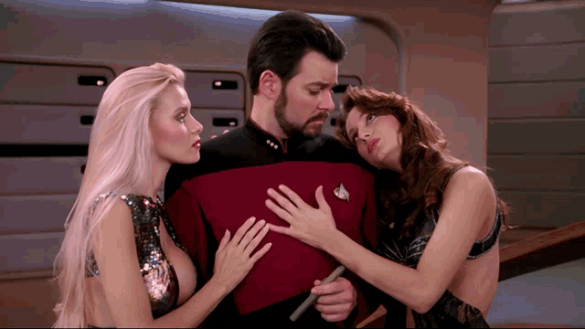 a man in a red uniform is surrounded by two women one of whom is touching his chest