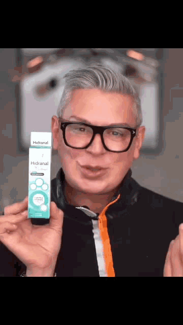 a man wearing glasses is holding a box of a product