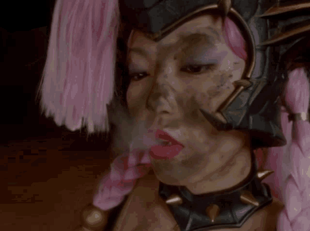 a woman with pink hair and a black helmet on her head smoking a cigarette