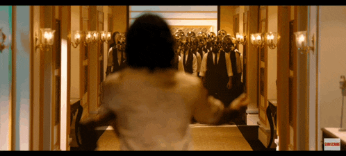 a person walking down a hallway with a subscribe button on the bottom right