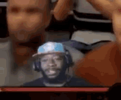 a man in a hat and headphones is sitting in front of a screen .