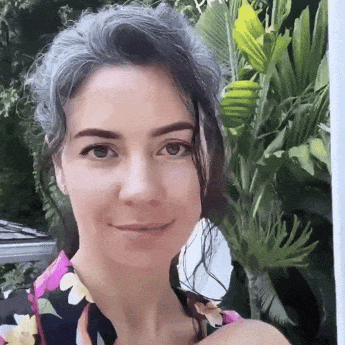 a woman with gray hair is wearing a floral shirt