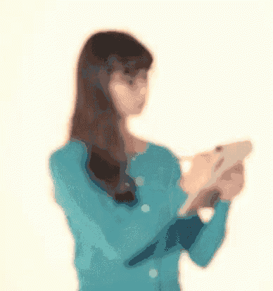 a woman in a blue sweater is looking at a tablet computer .