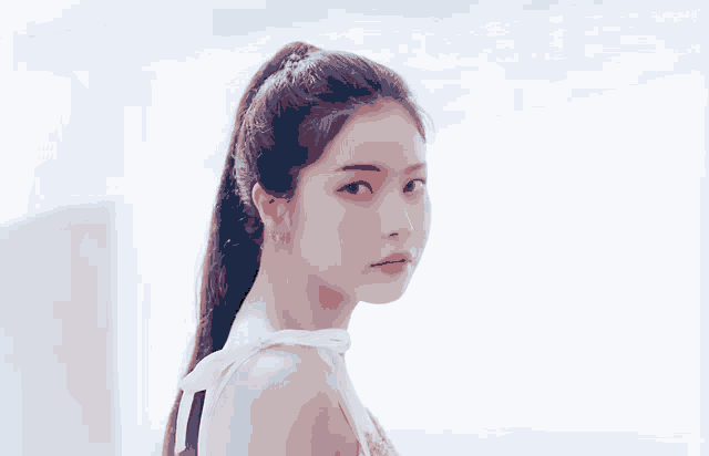 a close up of a woman 's face with a ponytail and a white background