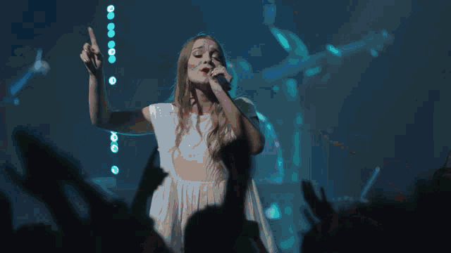 a woman in a white dress sings into a microphone