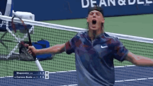 a man holding a tennis racquet on a tennis court with a scoreboard behind him that says shapoviov