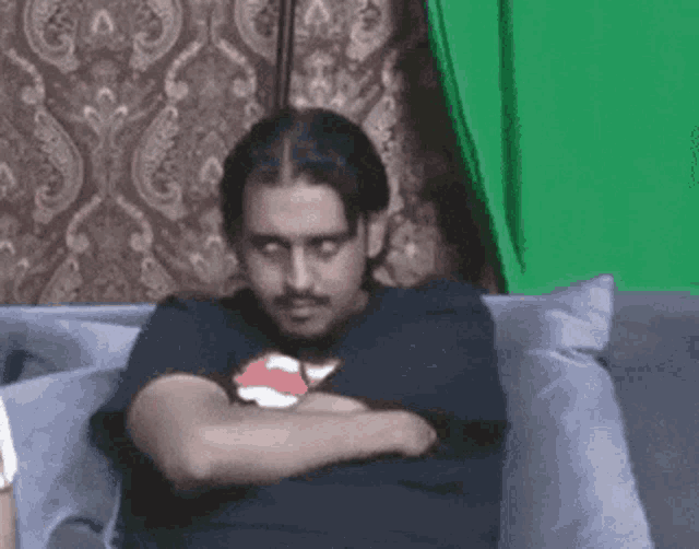 a man is sitting on a couch with his arms crossed and looking at the camera .