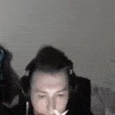 a man is smoking a cigarette while wearing headphones and a mask .