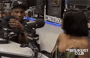a man is talking to a woman in front of a microphone at the breakfast club .