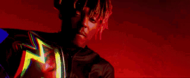a man with dreadlocks is standing in front of a fire and looking at the camera .