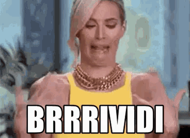 a woman in a yellow tank top is making a funny face while holding her hands up and saying brrrividi .