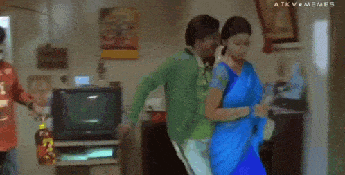 a woman in a blue saree is standing next to a man in a green shirt and says " give me samantha "