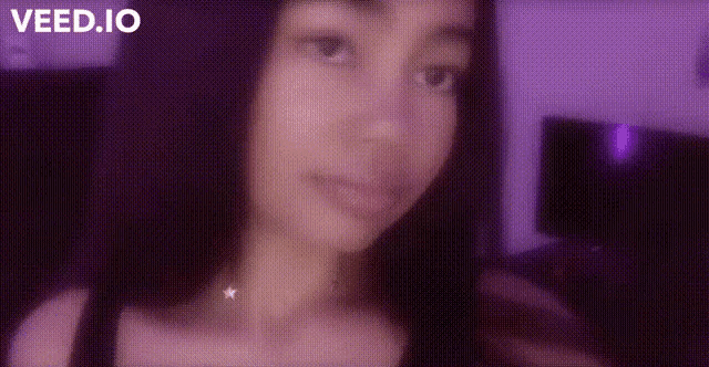 a close up of a woman 's face with a purple background and a star necklace .