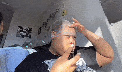 a man is laying on a bed wearing a face shield and making a funny face .