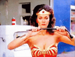 a woman in a wonder woman costume is holding a whip in her hands
