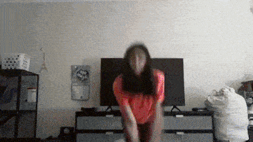 a woman in a red shirt is dancing in front of a tv with a sticker on the wall that says i love you magic