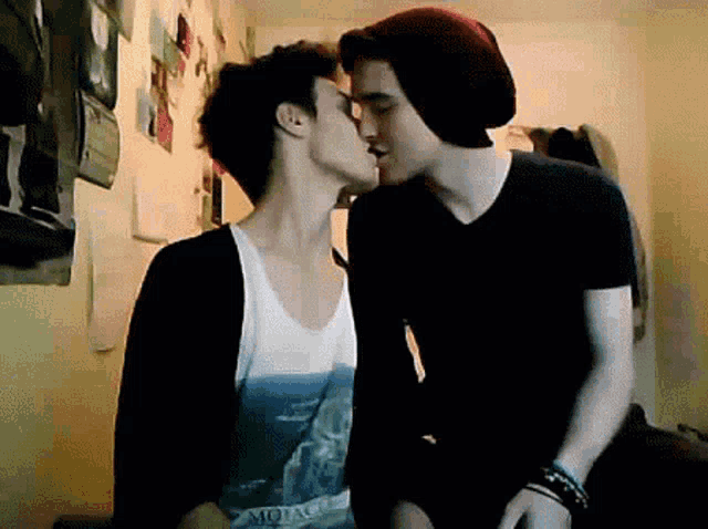 two young men are kissing in a room and one of them is wearing a shirt that says montana on it