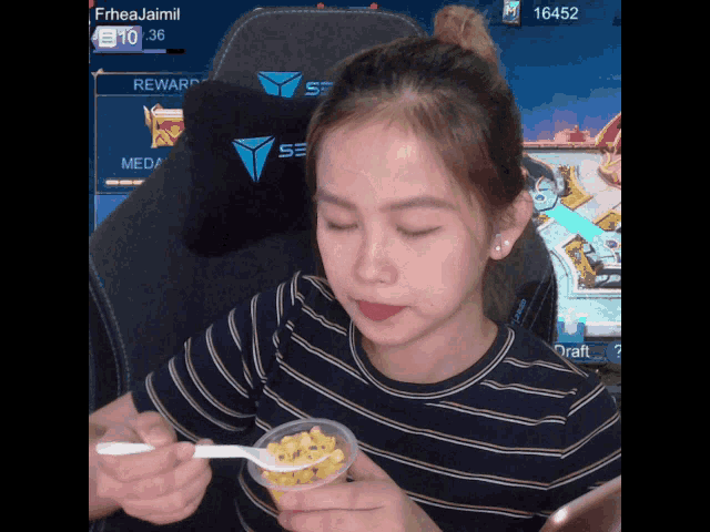 a girl is eating corn with a spoon in front of a screen that says rewards