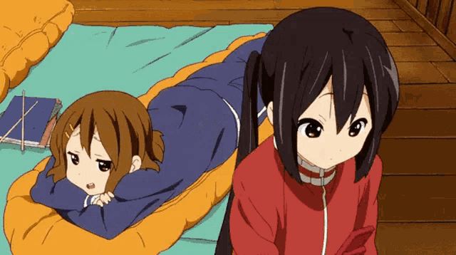 a couple of anime girls laying on a bed