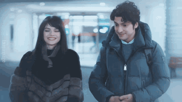 a man and a woman are standing next to each other and the man has a backpack