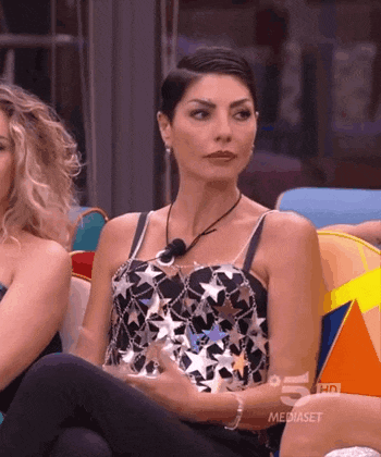 a woman in a black top with stars on it is sitting next to another woman on a couch .