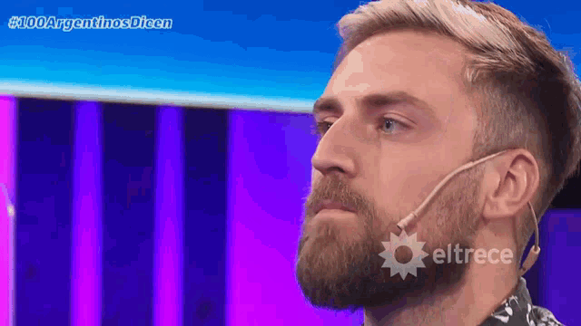 a man with a beard is wearing a microphone and the word eltrece is on the bottom