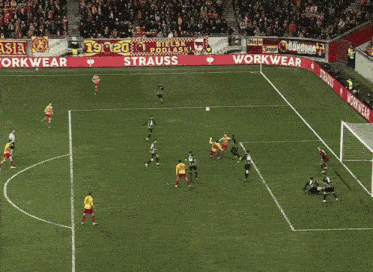 a soccer goalie jumps to catch a ball in front of a sign that says workwear russia.com