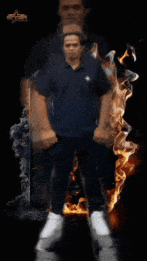 a man in a blue shirt is surrounded by a circle of flames