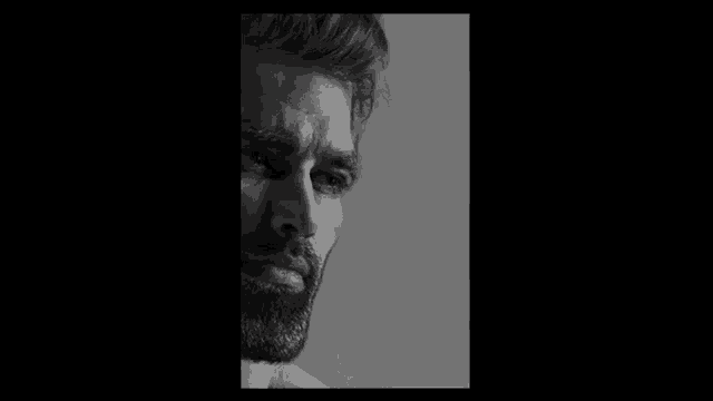 a shirtless man with a beard is smiling in a black and white photo
