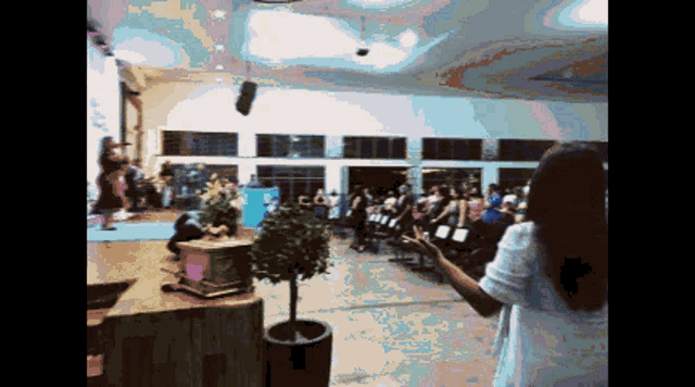 a woman in a white dress stands in front of a crowd at a church