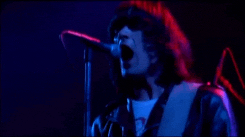 a man is singing into a microphone while playing a guitar on stage .